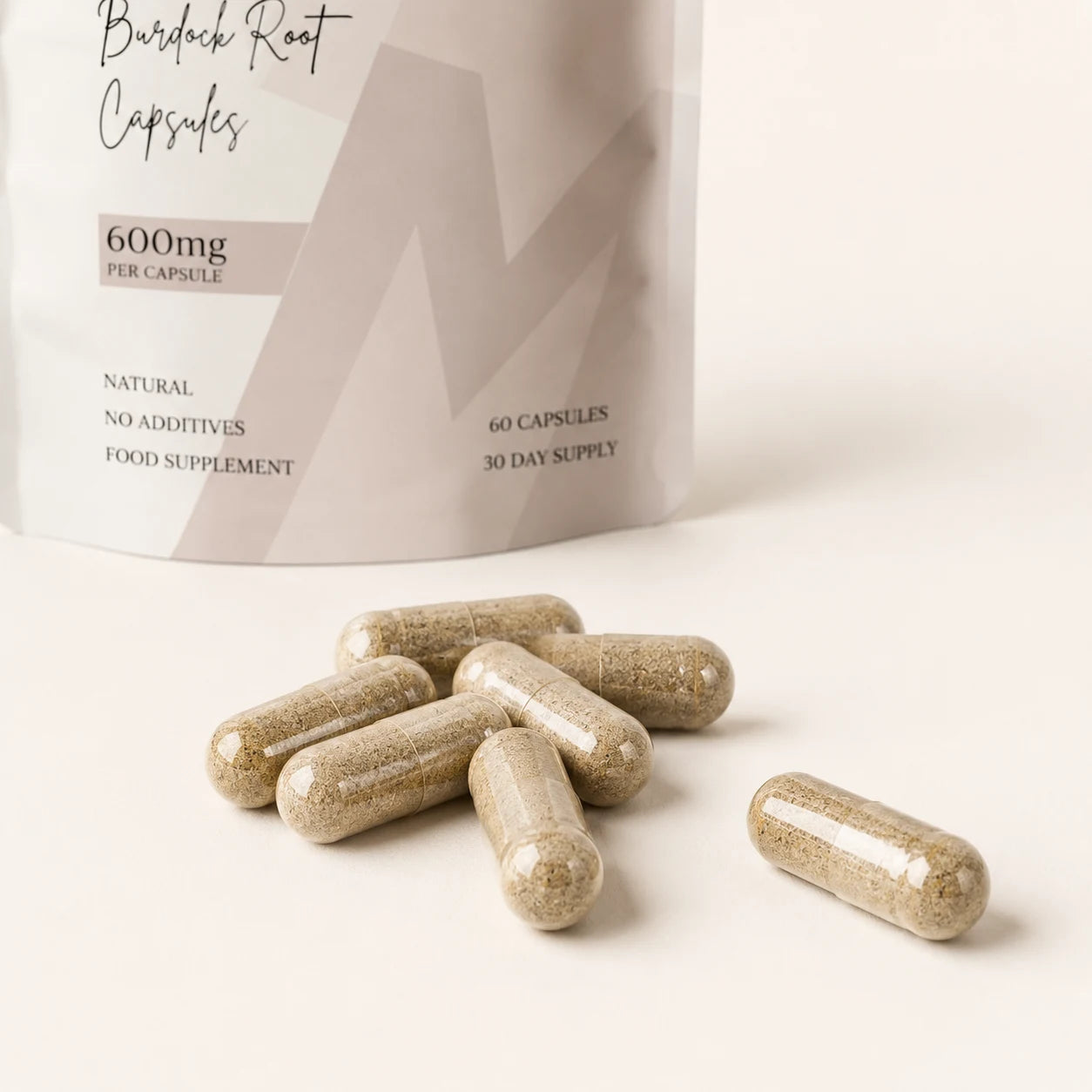 Close-up of Millie’s Moss Burdock Root Capsules with beige plant-based capsules in front of the product pouch