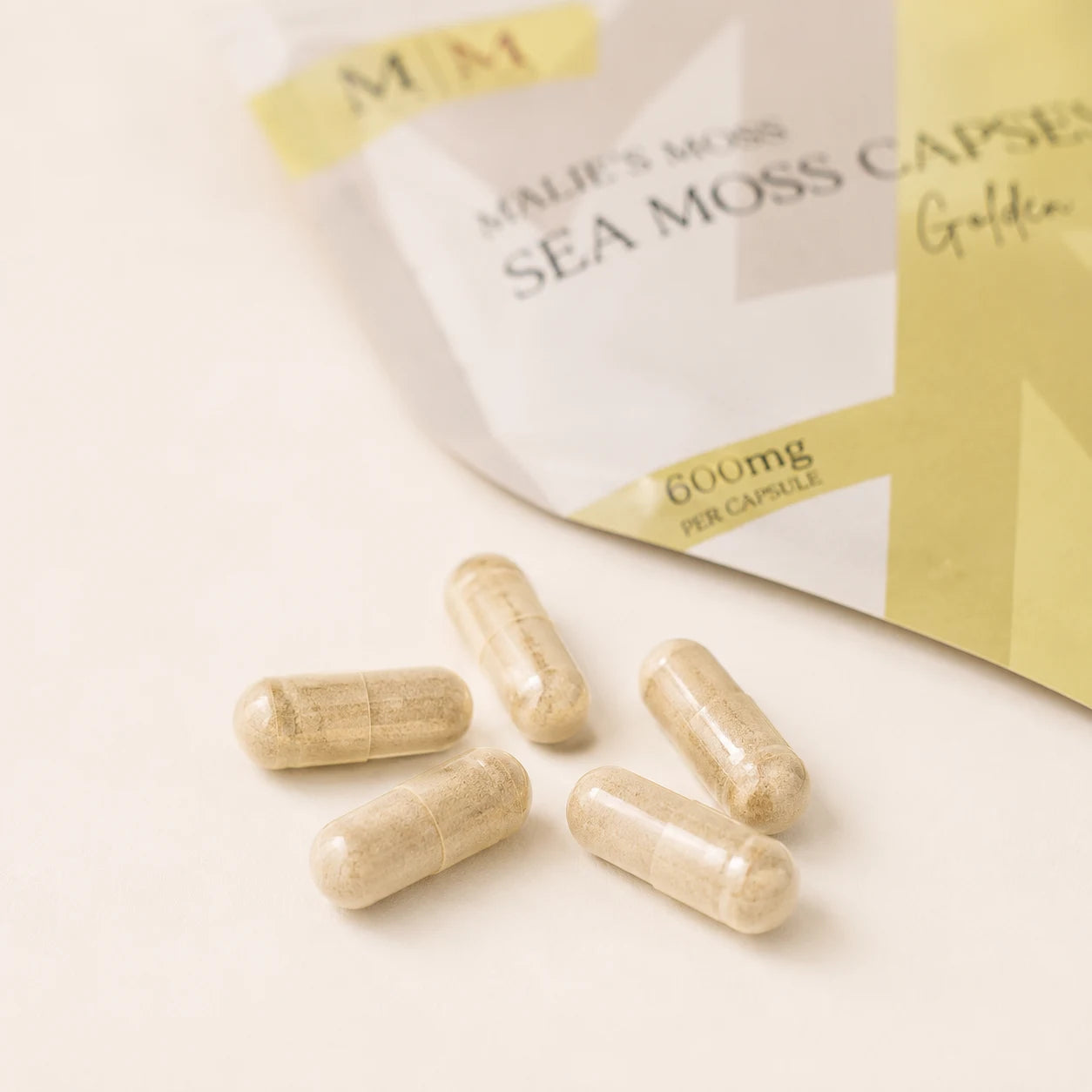 Close-up of Millie’s Moss Golden Sea Moss Capsules showing golden capsules in front of the product pouch.
