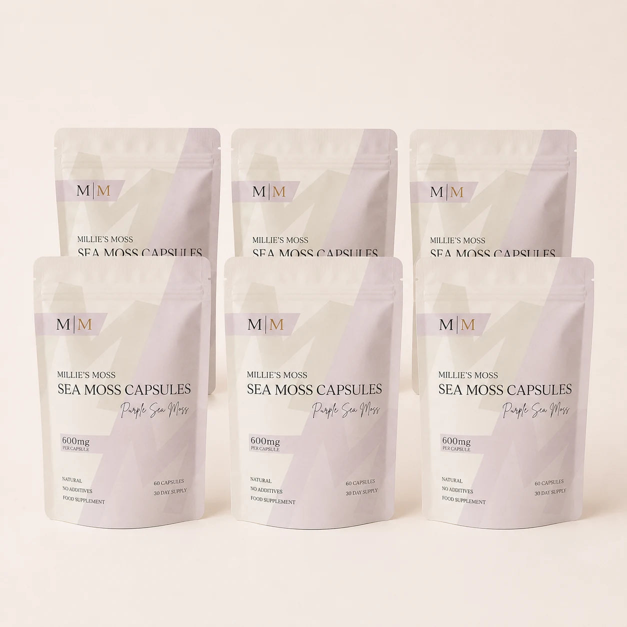 Six-pack bundle of Millie's Moss Purple Sea Moss Capsules on a warm off-white background.