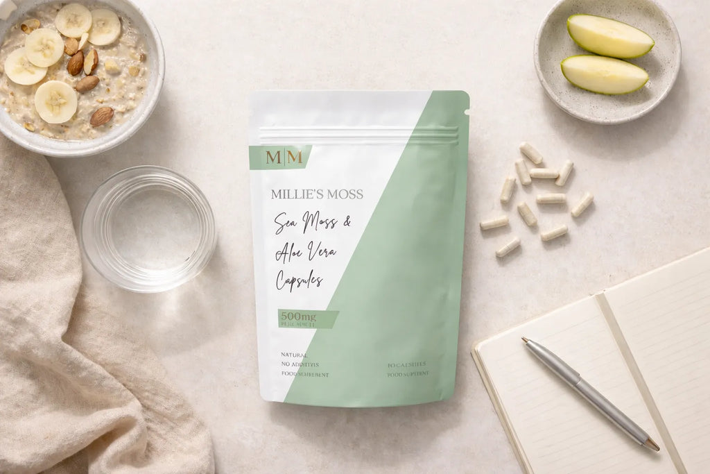 Flat lay of sea moss and aloe vera capsules with breakfast bowl, apple slices, and notebook for a daily wellness routine.