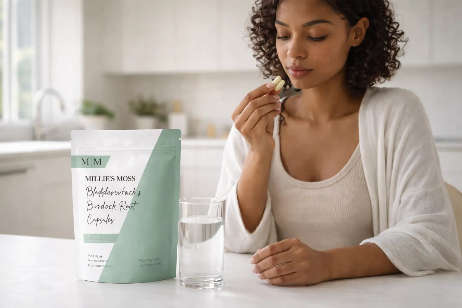 Woman enjoying tea during a morning wellness routine with Millie’s Moss bladderwrack and burdock root capsules on the table.