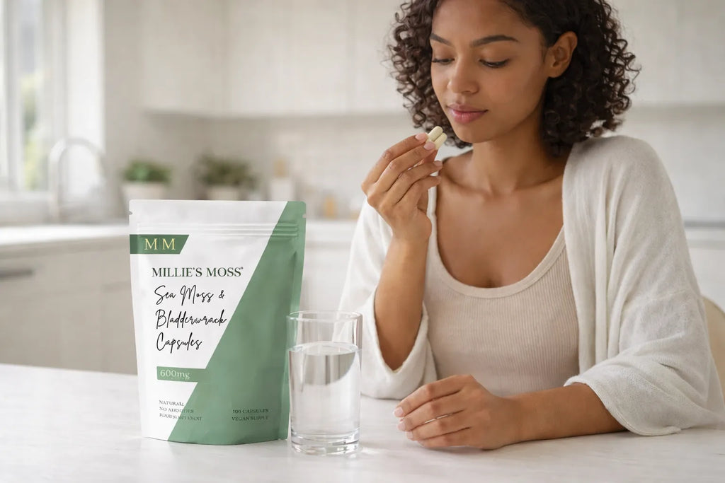 Woman taking sea moss and bladderwrack capsules with water as part of a healthy daily supplement routine.
